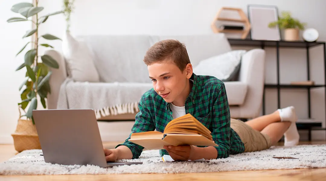 Boy reading while looking at laptop